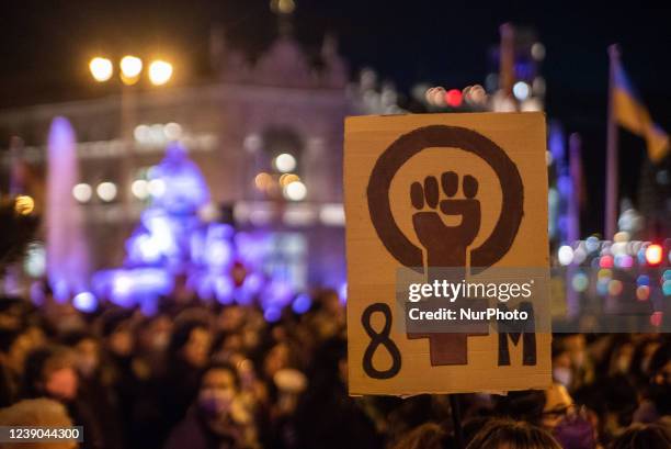 Banner with the 8M logo with Cibeles lit purple on the back in Madrid, Spain, on March 8, 2022 during the International Women's Day.