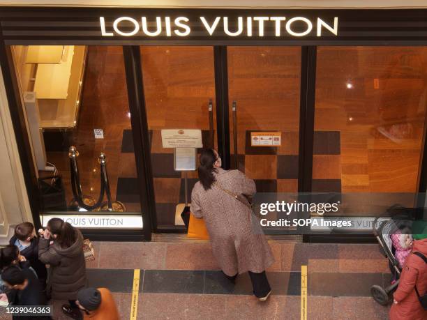 Woman looks through the glass doors of a closed Louis Vuitton boutique. Major international premium brands have ceased their activities in Russia, by...