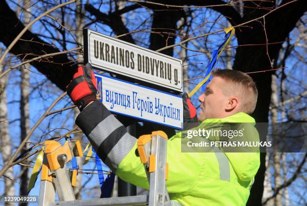 Worker fixes street plates in Lithuanian and in Ukrainian languages reading "Ukrainian Heroes Street" in a hitherto nameless road leading straight to...