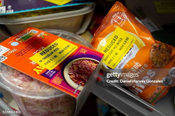 Selection of basic goods such as microwave rice that have been reduced and labelled with yellow stickers, marking them as cut cost goods, in a...