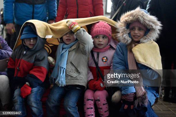 Four children share a blanket to get warm at the Lviv railway station as people board evacuation trains to Poland, Lviv, western Ukraine. Ukraine has...