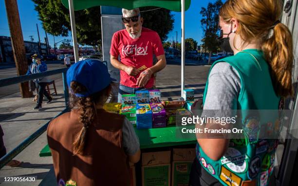 Chris Hillman, middle, buys Girl Scout Cookies from Madar Mee right, and Emma Diaz left, in the Mar Vista neighborhood at on Friday, Feb. 11, 2022 in...