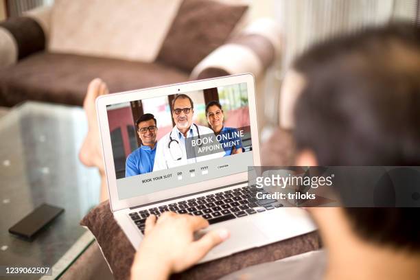booking online appointment with doctors using laptop at home - doctor looking over shoulder stock pictures, royalty-free photos & images