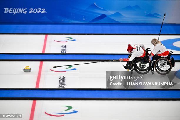 Switzerlands Hans Burgener curls the stone during the round robin session 15 game at the Beijing 2022 Winter Paralympic Games wheelchair curling...