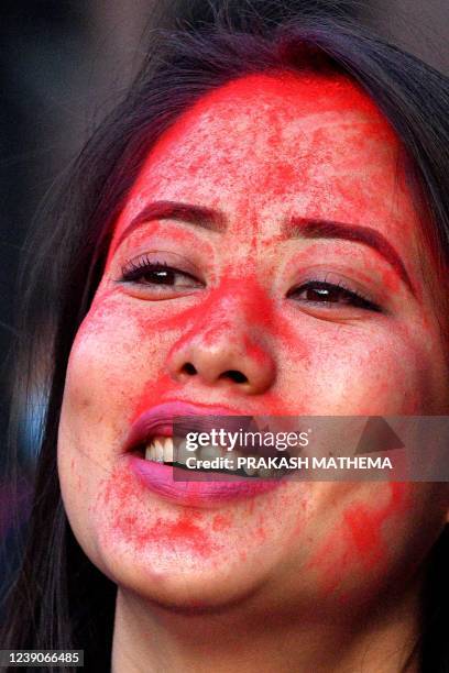 Woman looks on with her face coved in coloured powder also known as Gulal during a celebration to mark the beginning of Holi, the festival of...