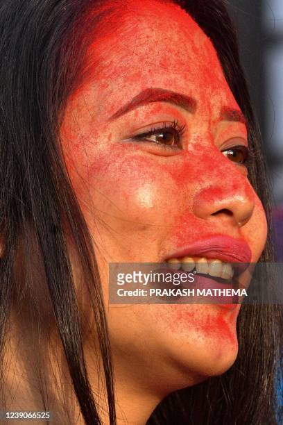 Woman looks on with her face coved in coloured powder also known as Gulal during a celebration to mark the beginning of Holi, the festival of...