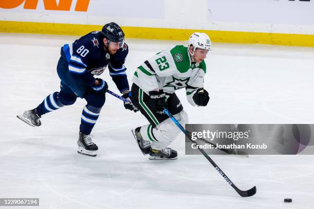 Esa Lindell of the Dallas Stars plays the puck up the ice while Pierre-Luc Dubois of the Winnipeg Jets gives chase during third period action at...