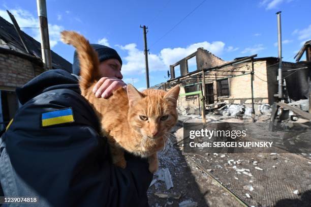 Rescuer holds a cat among deserted homes, damaged by Russian shelling, near the frontline village of Horenka, north of Kyiv, on March 10 15 days...