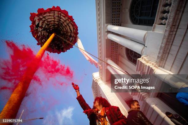 Man throws vermilion powder after hoisting a colourful pole or "chir", to mark the beginning of Holi festival in Kathmandu. The Holi festival also...