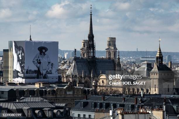 This general view taken on March 9, 2022 shows a rooftop of Paris, the Sainte-Chapelle church and an advertising board displayed for French...