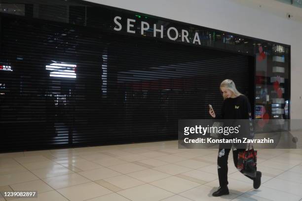 Shopper walks in front of closed Sephora cosmetics store, in Russia, March 2022, in Moscow, Russia. Sephora, Puma, Louis Vuitton, Dior, Levi's,...