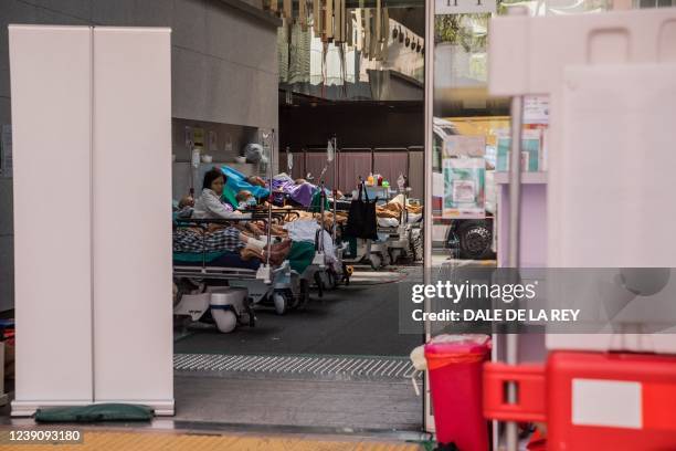 Patients lie in beds in a holding area next to the accident and emergency department of Princess Margaret hospital in Hong Kong on March 11, 2022 as...