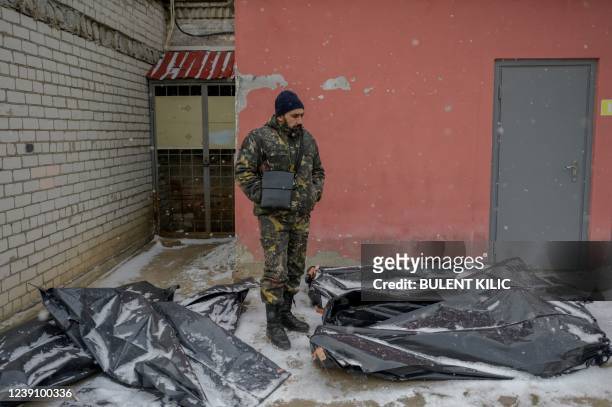 Ukrainian man in camouflage stands next to snow covered body bags in the yard of a morgue in Mykolaiv, a city on the shores of the Black Sea that has...