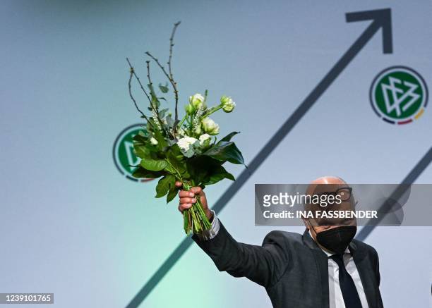 The newly elected president of the German Football Federation Bernd Neuendorf holds a bouquet of flowers as he stands on stage during an...