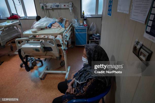 Relative of an Iranian elderly man who is infected by COVID-19, wearing a protective face mask while sitting next to her patient hospital bed at a...