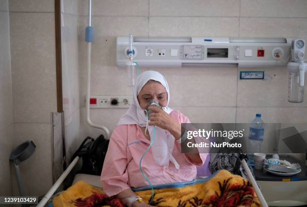 An Iranian elderly woman who is infected by COVID-19 uses oxygen while sitting on a hospital bed at a COVID-19 ward in a hospital in the holy city of...