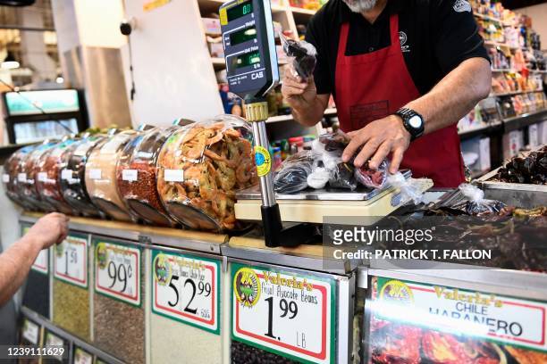 Clerk weighs dried peppers for a customer inside Grand Central Market on March 11, 2022 in downtown Los Angeles, California. - US consumer prices hit...