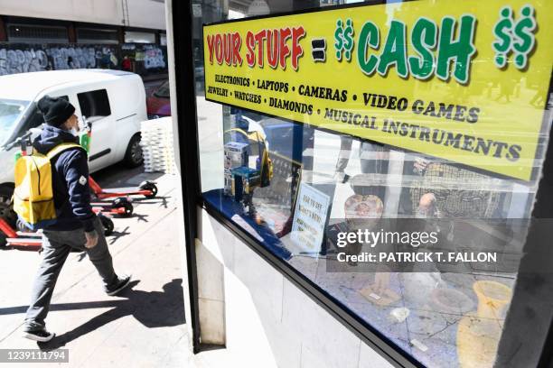 Pedestrian walks past signage offering cash for valuables outside of a pawn shop on March 11, 2022 in downtown Los Angeles, California. - US consumer...