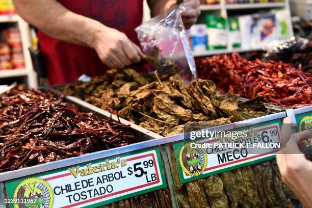 Clerk bags dried peppers for a customer inside Grand Central Market on March 11, 2022 in downtown Los Angeles, California. - US consumer prices hit a...