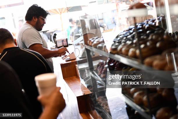 Customer uses a credit card terminal to make a purchase at The Donut Man inside Grand Central Market on March 11, 2022 in downtown Los Angeles,...