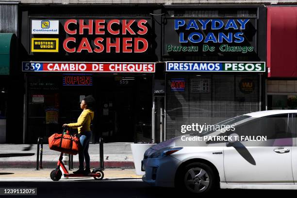 Person rides a scooter past a check cashing and payday loans store on March 11, 2022 in downtown Los Angeles, California. - US consumer prices hit a...