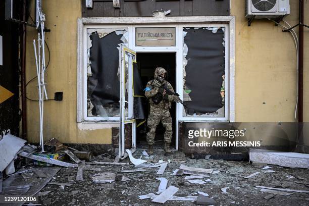 Ukrainian serviceman exits a damaged building after shelling in Kyiv, on March 12, 2022. - Russian forces are positioned around Kiev on March 12,...