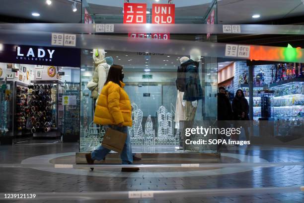 Woman walks past a Uniqlo store in Moscow. The Japanese casual wear designer, manufacturer, and retailer has decided to temporarily suspend its...