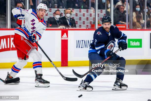 Filip Chytil of the New York Rangers and Dylan DeMelo of the Winnipeg Jets keep an eye on the puck during second period action at Canada Life Centre...