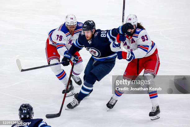Pierre-Luc Dubois of the Winnipeg Jets skates through K'Andre Miller and Mika Zibanejad of the New York Rangers during first period action at Canada...