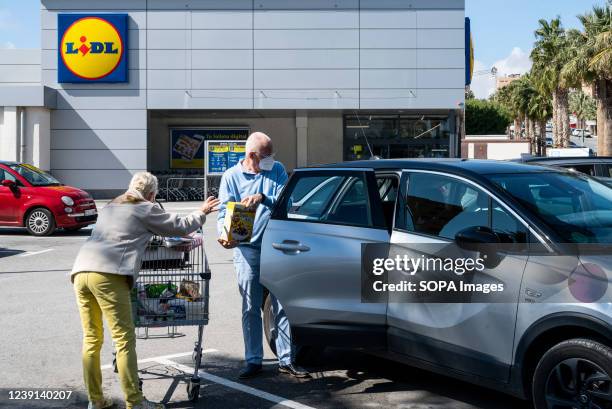 Customers place their groceries inside their car as they leave the German international discount retail chain supermarket, Lidl, seen in Spain.