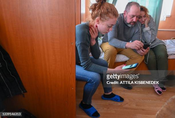 Displaced Ukrainian family read the news on smartphones in a Hungarian-language boarding school in Berehove, western Ukraine, on March 7, 2022. -...