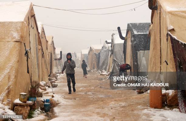 People walk between tents at a camp for internally displaced Syrians, near the town of Kafr Lusin, by the border with Turkey in the rebel-held...
