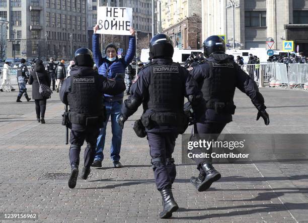 Russian Police officers run to detain a man holding a poster reads: "No war" during a unsanctioned protest rally at Manezhnaya Square in front of the...