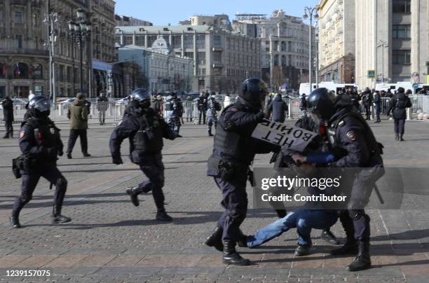 Russian Police officers detain a man holding a poster reads: "No war" during a unsanctioned protest rally at Manezhnaya Square in front of the...