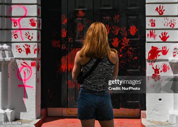 Woman looks at graffiti related to feminism and the vandalized front door of the University's Faculty of Law in the center of San Cristobal de las...