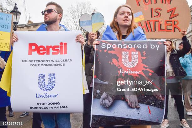 Protesters hold placards demanding that Unilever stops doing business in Russia, during the demonstration. Thousands of protesters gathered outside...