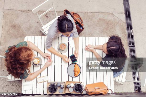 overhead view of three women having a lunch time discussion. - restaurant women friends lunch stock pictures, royalty-free photos & images