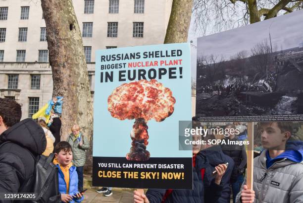 Protester holds a placard warning of a nuclear disaster, during the demonstration. Thousands of protesters gathered outside Downing Street in support...