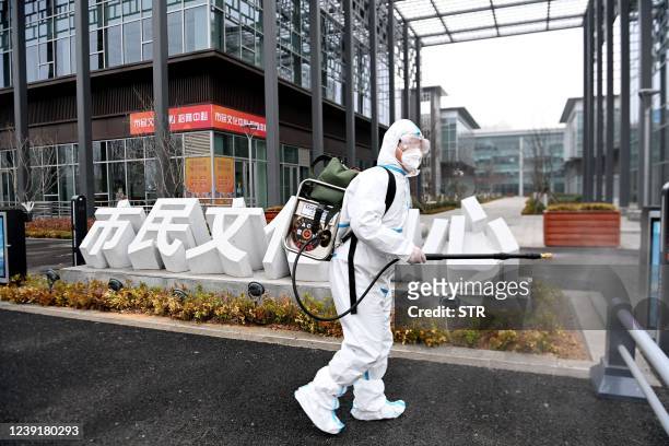 This photo taken on March 13, 2022 shows a staff member spraying disinfectant outside a library in Qingdao in China's eastern Shandong province. -...