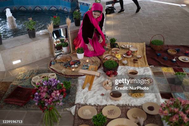 An Iranian woman sits next to a Haft-Seen table which is the main symbol of Iranian New Year, during a ceremony to mark Nowruz in the Art Museum...