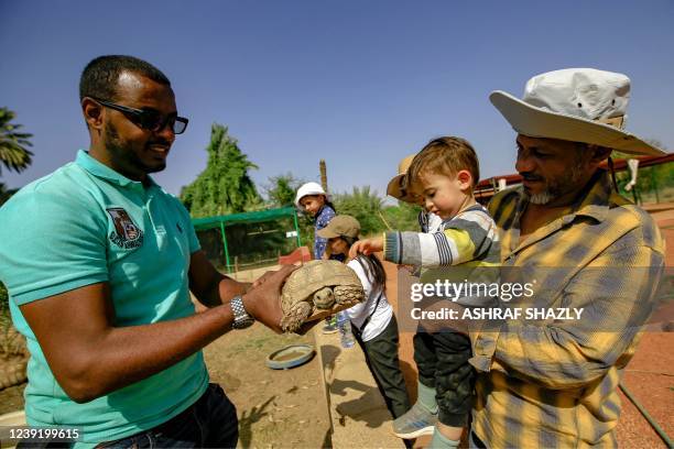 Othman Muhammad Salih, founder of the Sudan Animal Rescue centre, holds a turtle up to be touched by a visiting child at the facility in Al-Bageir...