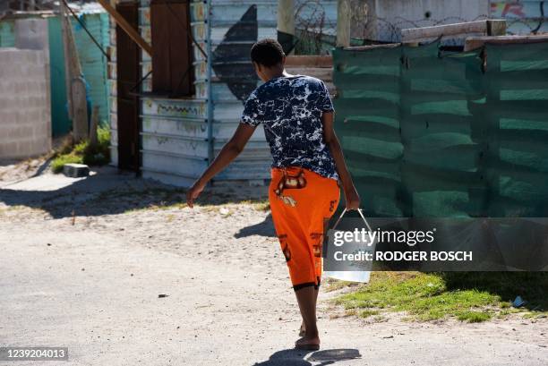 Woman carries a bucket of water which she filled at a nearby tap in Zwelitsha, an informal settlement in Khayelitsha that is home to millions of...