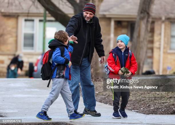 Parent greets his son's friend as students arrive at Rogers Fine Art Elementary School in Chicago, the United States, on March 14, 2022. Chicago...