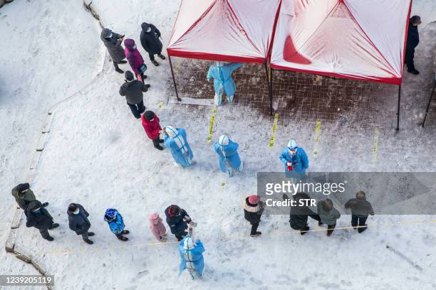 Residents queue to undergo nucleic acid tests for the Covid-19 coronavirus in Jilin in China's northeastern Jilin province on March 15, 2022. - China...