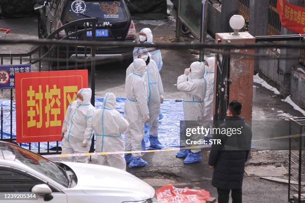 Staff members wearing personal protective equipment stand at the entrance to a residental area which is restricted due to a recent outbreak of the...