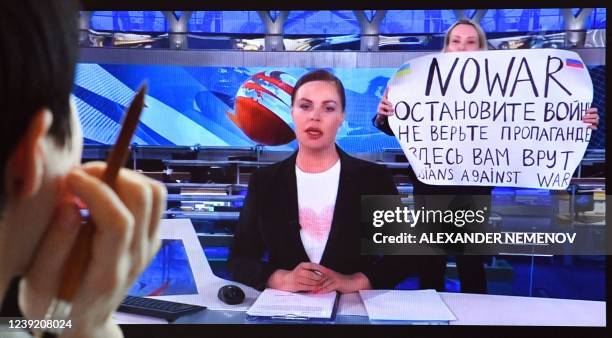 Woman looks at a computer screen watching a dissenting Russian Channel One employee entering Ostankino on-air TV studio during Russia's most-watched...