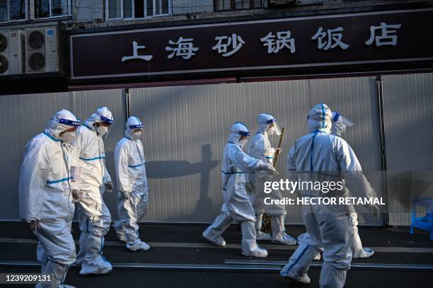 Workers work in wearing protective clothes in an area where barriers are being placed to close off streets around some lockdown areas after the...