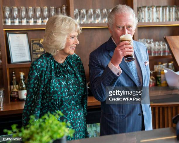 Prince Charles, Prince of Wales sips a pint of Guinness he has poured as he stands next to Camilla, Duchess of Cornwall during a visit to The Irish...