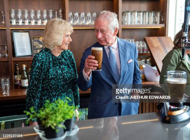Britain's Camilla, Duchess of Cornwall reacts as she watches Britain's Prince Charles, Prince of Wales take a drink of a pint of Guinness that he had...
