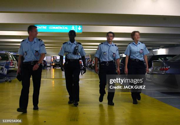 Des policiers de proximité du commissariat de Noisy-Le-Grand patrouillent dans le parking d'un centre commercial de la ville, le 19 juillet 2002,...